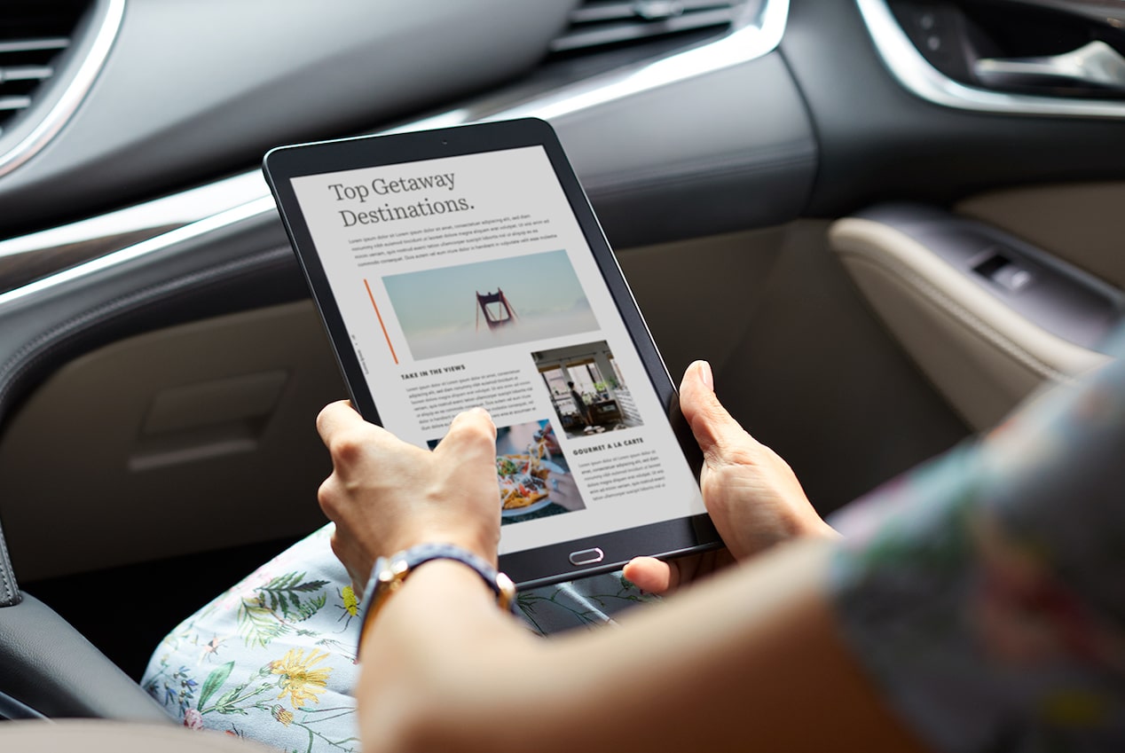 A Woman Sitting in a Buick Vehicle While Using an iPad To Display the MyBuick App