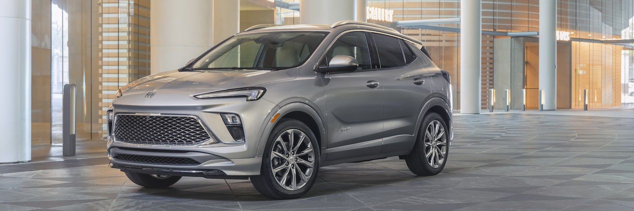 Three-Quarters View Of The 2024 Buick Encore GX Avenir Parked In Front Of Glass Building