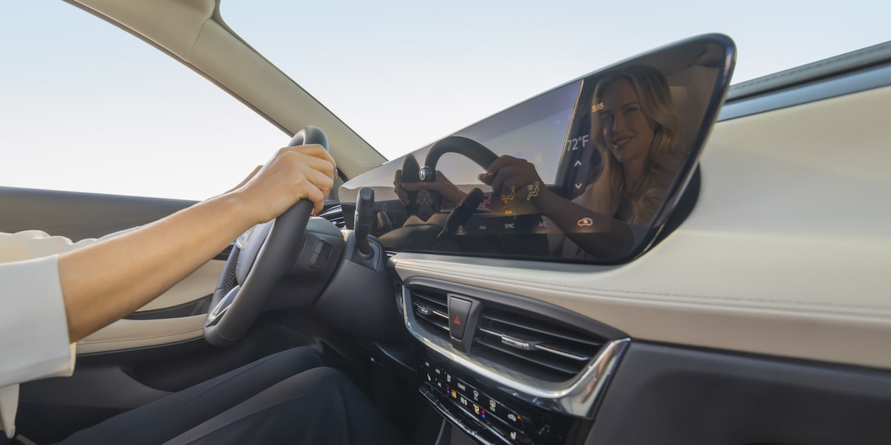 Woman's Reflection Displayed On Infotainment Touch Screen Inside The 2024 Buick Encore GX Avenir While Driving