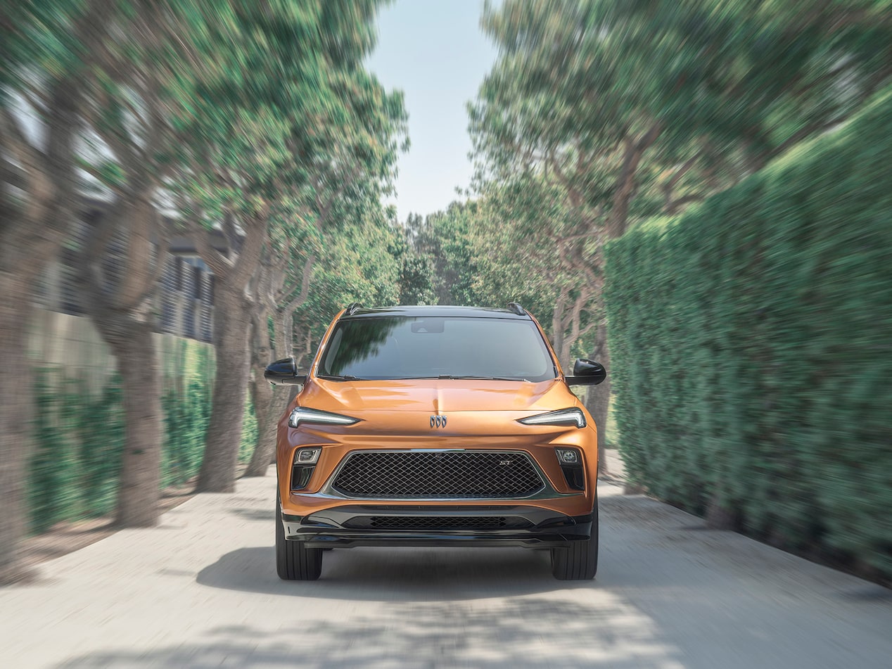 Head-On View Of The 2024 Buick Encore GX ST Driving Down Tree-Lined Road