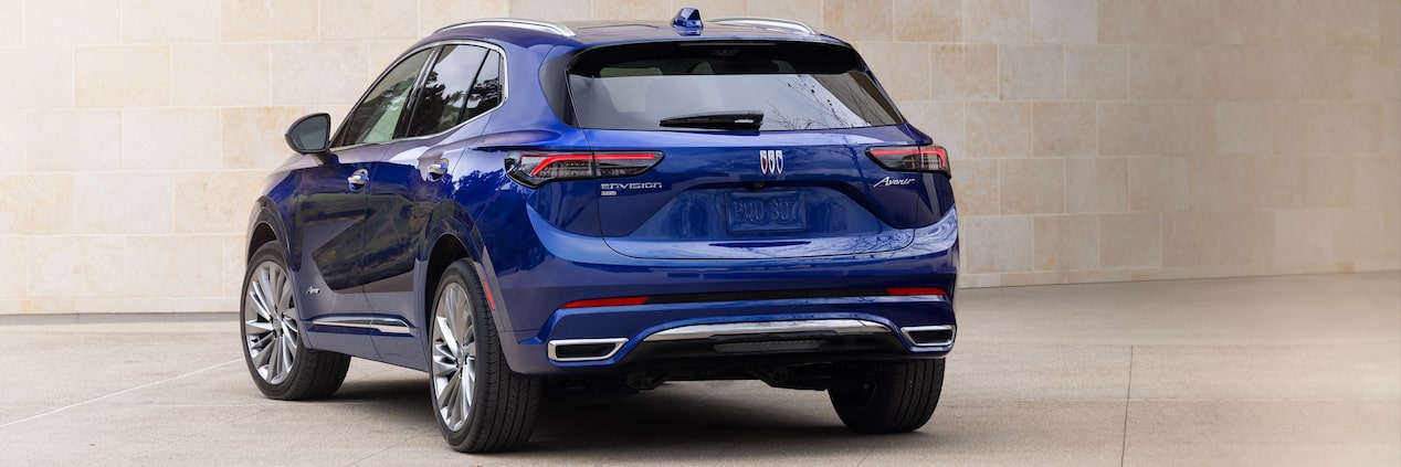 Wide Rear Three-Quarters View of the 2024 Buick Envision 5 Passenger SUV Parked In Front of a Building