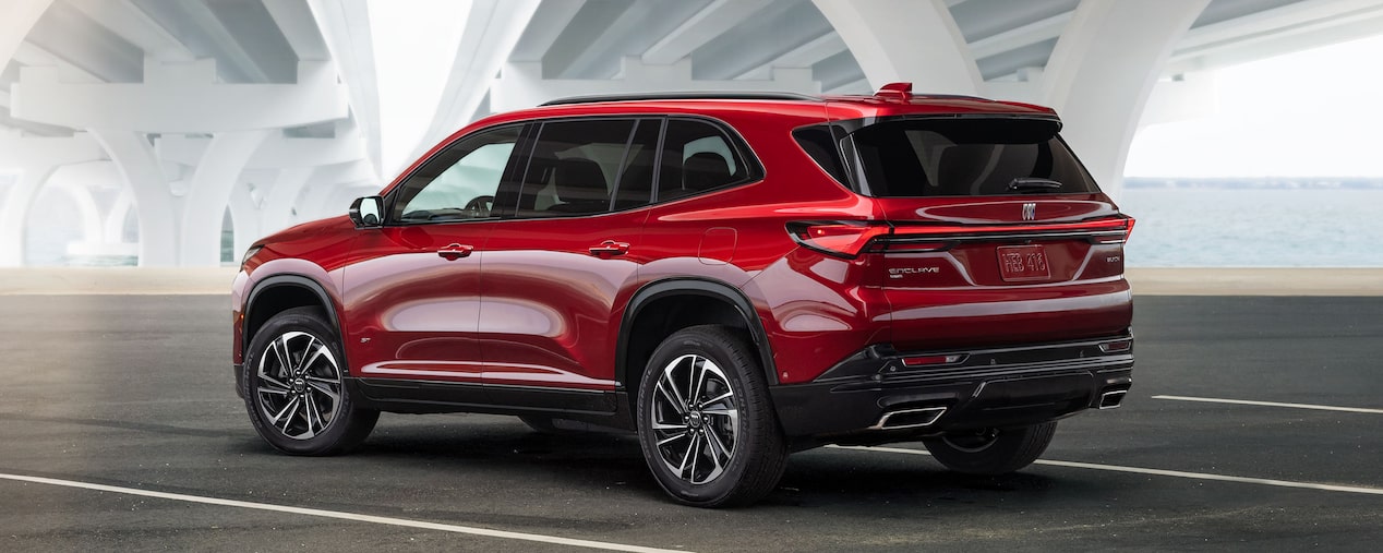 Three Quarters Rear View of a Red 2025 Buick Enclave Under a Bridge