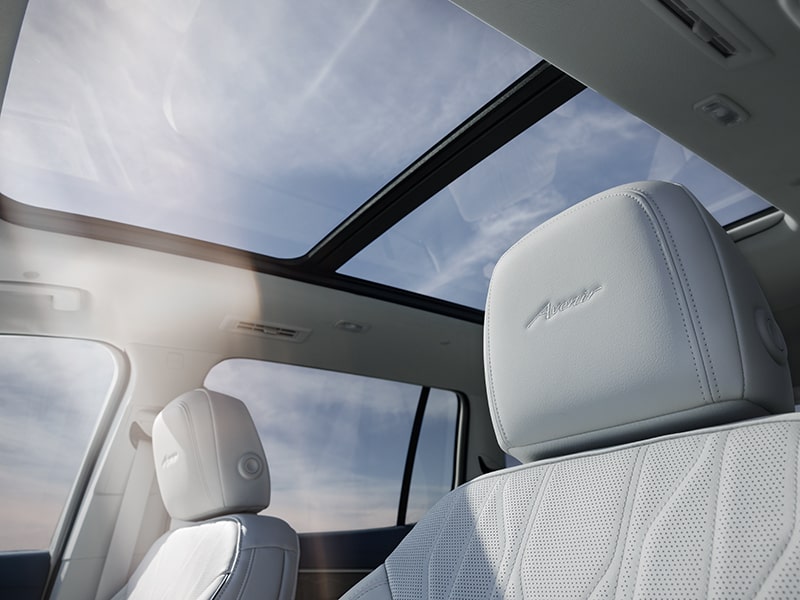 Front Seats in a 2025 Buick Enclave Avenir Luxury SUV with Sunlight Coming from the Moonroof