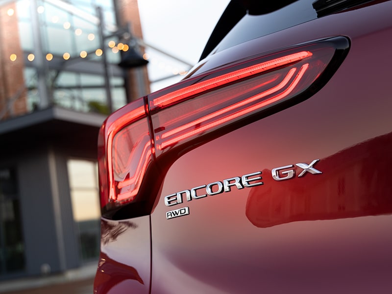 Close-up Exterior View of a Red 2025 Buick Encore GX Tail Lamp and Model Logo