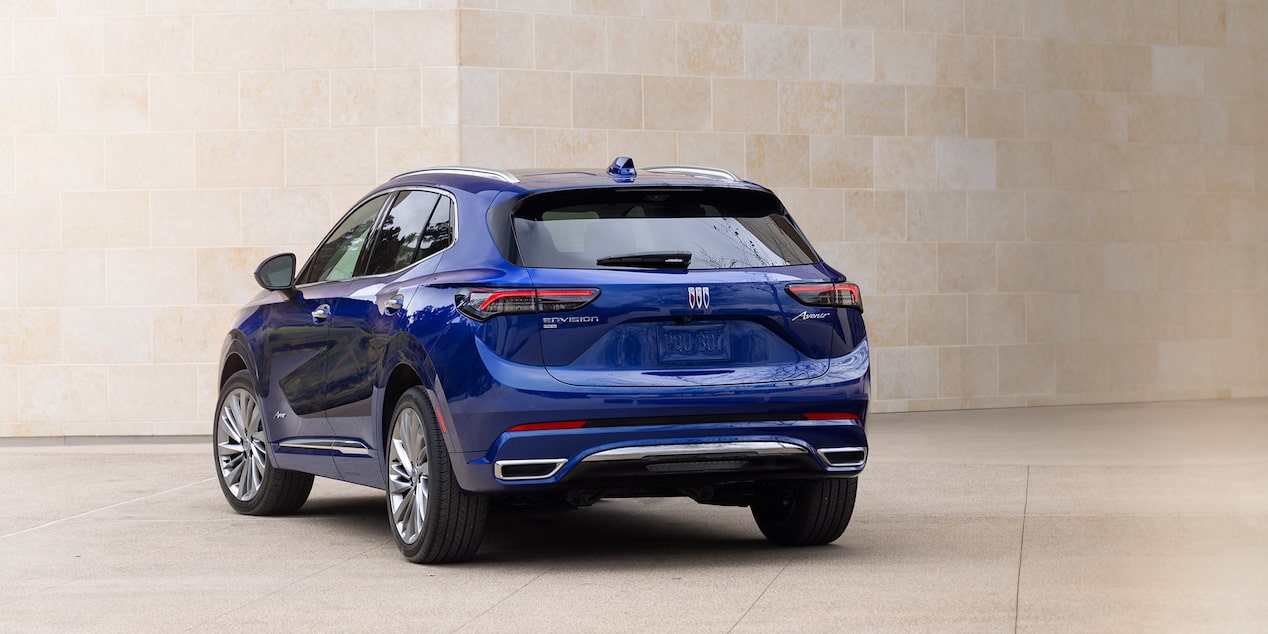 Wide Rear Three-Quarters View of the 2025 Buick Envision Avenir Luxury SUV Near a Concrete Building