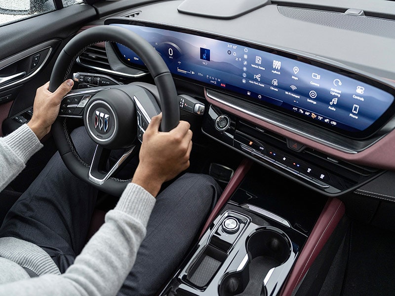 Overhead View of the Interior of a 2025 Buick Envision ST Sporty SUV with a Person Sitting in the Driver's Seat and Holding the Steering Wheel