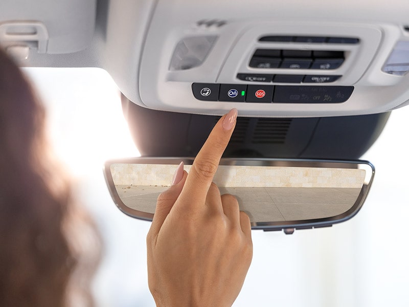 Close-up of a Person Reaching to Press the OnStar Button in a 2025 Buick Envision Compact SUV