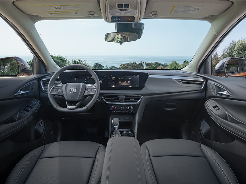 Wide Interior View of the Encore GX Sport Touring SUV’s Front Seating, Infotainment Screen, and Steering Wheel