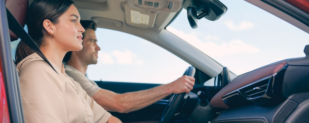 Side View of a Man Driving a Buick Vehicle with a Woman Next to Him in the Passenger Seat