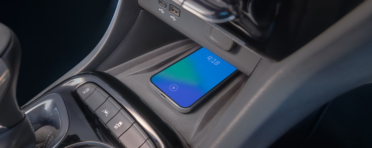 A Phone on the Wireless Charging Compartment Next to the Gear Shift Stick Inside a Buick SUV