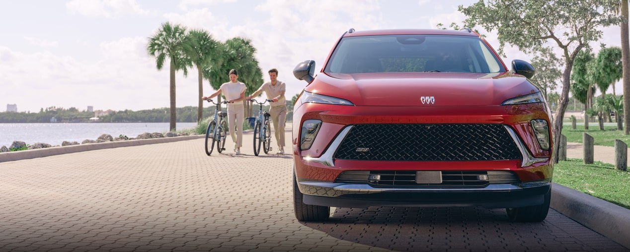 Couple walking their bikes next to Buick vehicle