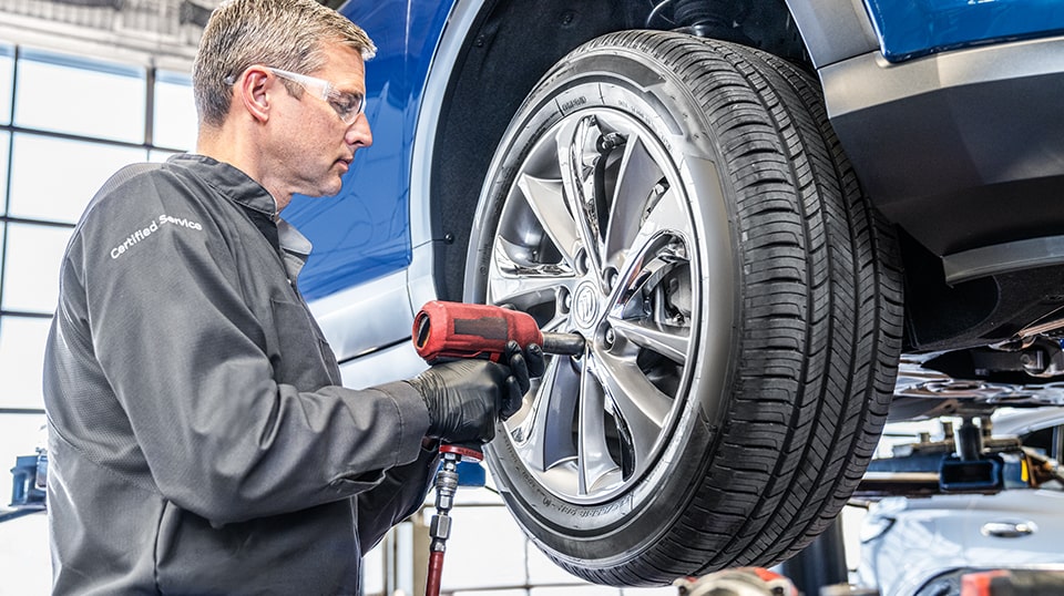 Buick Certified Service Technician Tightening Bolts on a Vehicle's Wheel