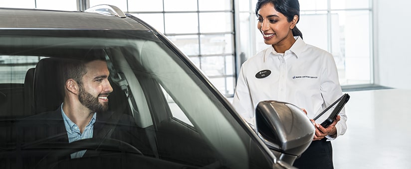 Buick Certified Service Representative Speaking with a Buick Customer Sitting in Their Car