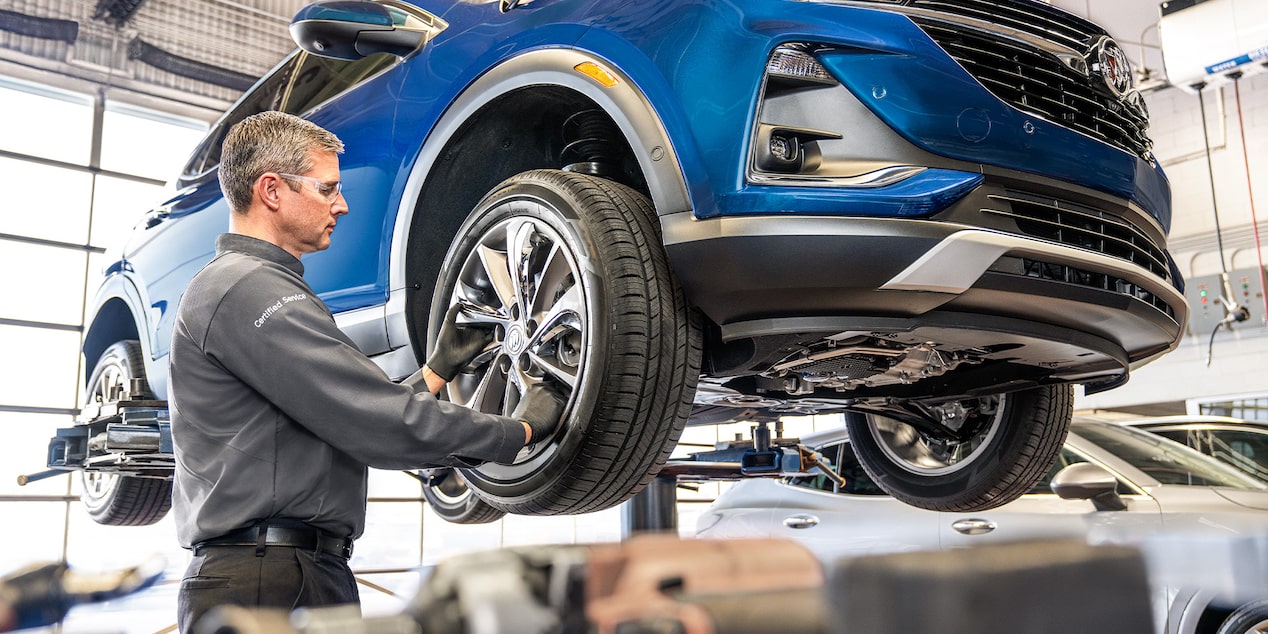 Buick Certified Service Technician Performing a Tire Rotation on a Vehicle