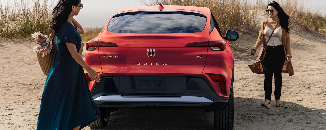 A Couple Sits on the Trunk of Their Buick Enclave While Enjoying the Breathtaking Views of the Mountains